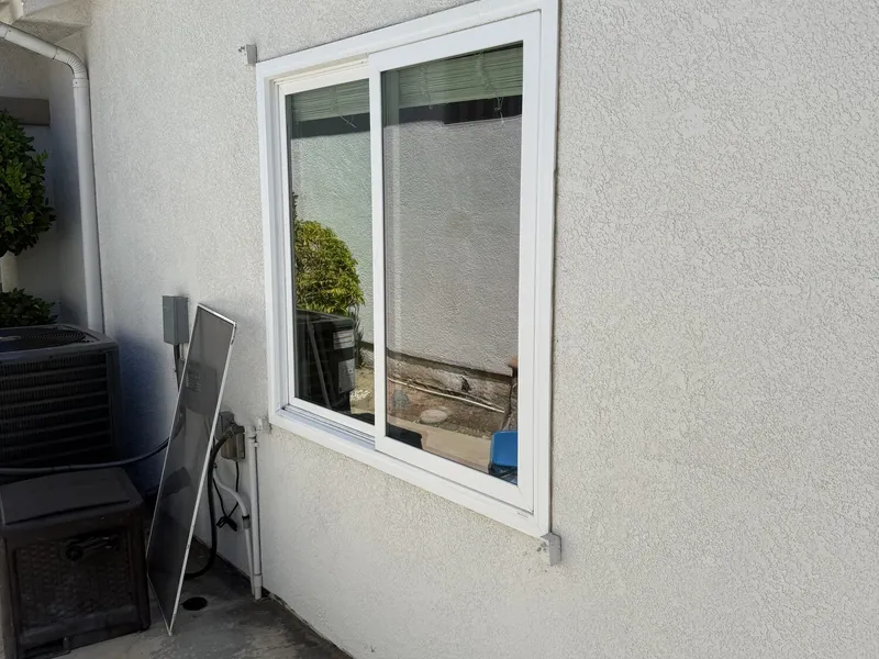 Two window screens stood against a stucco wall beside the window they came out of.