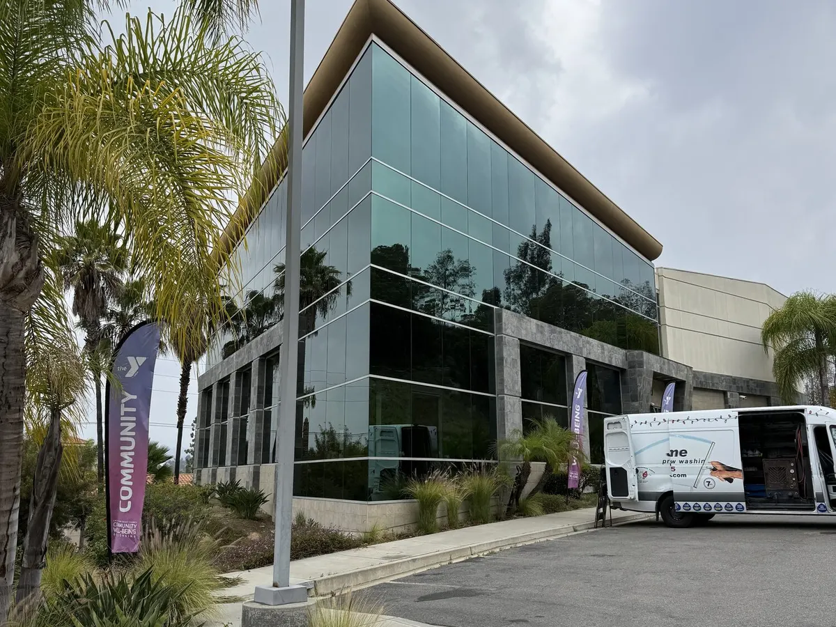 A modern commercial building with a full glass elevation, the Flex Home Services van parked alongside it.
