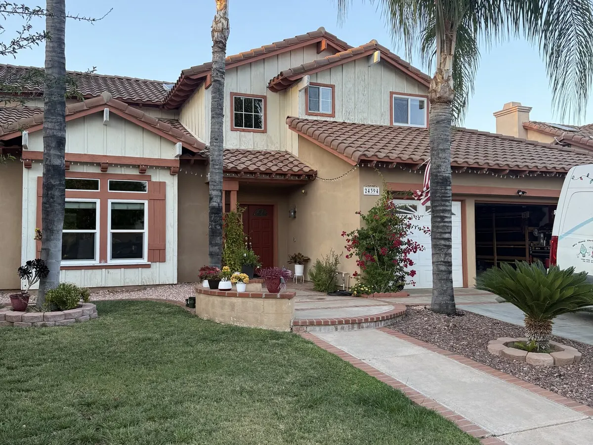 A Spanish style home with palms and a red front door, the Flex van parked in the driveway to the right.